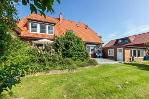 a house with an orange roof and a yard at Fewo Freiraum mit großer Terrasse in Friedrichskoog
