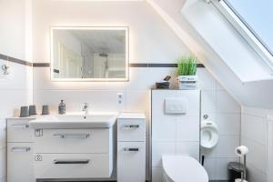 a white bathroom with a sink and a toilet at Fewo Kleine Auszeit 100qm in Friedrichskoog +23 photos