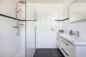 a white bathroom with a shower and a sink at Fewo Freiraum mit großer Terrasse in Friedrichskoog +28 photos