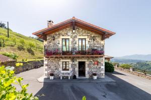 a stone house with a balcony on a hill at La Cabaña de Manuela in Bustantegua