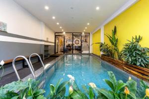 a swimming pool in the middle of a building with plants at Two Horses Hostel in Hoi An