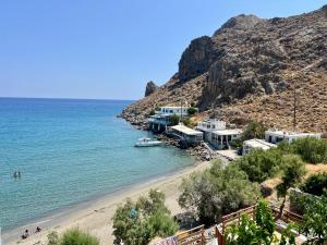 a beach with houses on a hill next to the ocean at Blue Thea in Lentas