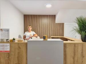 Ein Mann sitzt an einem Tresen in einem Büro in der Unterkunft Sagra Hotel in Alicante