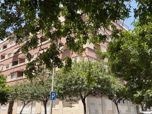 ein rosafarbenes Gebäude mit Bäumen davor in der Unterkunft Sagra Hotel in Alicante