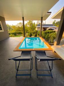a table and two chairs in front of a swimming pool at Hornbill Pool Villas 1 in Ko Chang