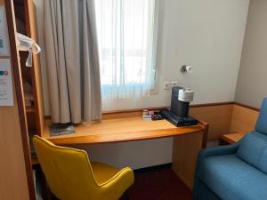 a room with a desk with a coffee maker and a chair at Brit Hotel Confort Montauban in Montauban