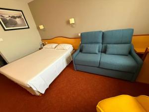 a bedroom with a bed and a blue couch at Brit Hotel Confort Montauban in Montauban