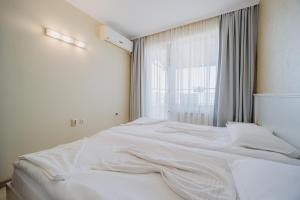a white bed in a room with a window at Seafront Apartment with Panoramic Terrace in Golden Sands