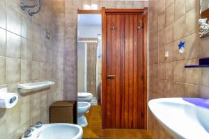 a bathroom with a toilet sink and a wooden door at Casa 2 Punta Negra Vista Mare in Stintino