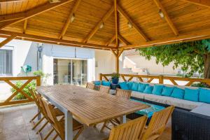 a wooden table and chairs on a patio with a couch at Studio piscine Alpilles in Noves