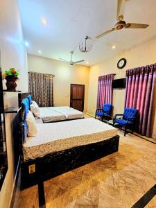 a bedroom with two beds and two chairs at Royal Villa in Karachi