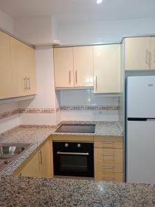 a kitchen with white cabinets and a sink and a refrigerator at Sol y playa in Palomares
