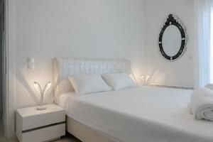 a white bedroom with a white bed and a mirror at Ciel Collection - Luxury Seafront Living in Perea