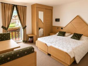 ein Schlafzimmer mit einem großen Bett und einem großen Fenster in der Unterkunft Hotel Ai Pini in Vigo di Fassa + 37 Fotos