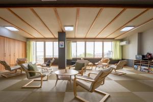 a waiting room with chairs and tables and windows at Beppu Ohana in Beppu