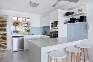 a kitchen with white cabinets and a counter with stools at Villa Seascapes in Coolum Beach