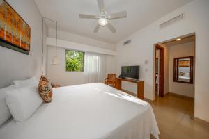 a bedroom with a white bed and a ceiling fan at Riviera Maya Suites in Playa del Carmen