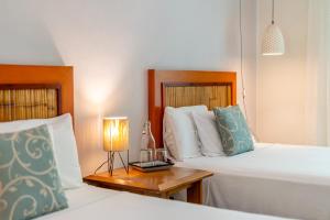 a bedroom with two beds and a table with a lamp at Riviera Maya Suites in Playa del Carmen