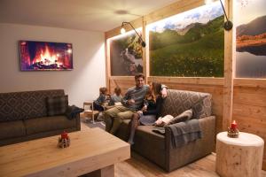 a family sitting on a couch in a living room at Residence & Wellness 3MILA in Peio Fonti