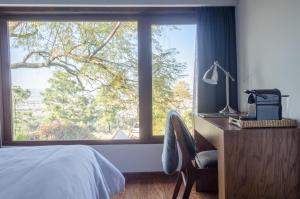 a bedroom with a bed and a desk and a large window at Maja Hotel Boutique in Morelia +37 photos