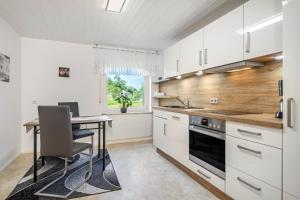 a kitchen with white cabinets and a table with a computer at Carmen in Wald
