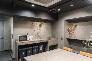 a dining room with a table and a microwave at MAIDO - Doyanen Hotels in Osaka