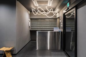 a restaurant lobby with a stainless steel counter and a chandelier at MAIDO - Doyanen Hotels in Osaka
