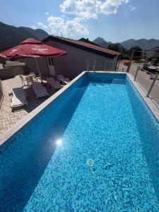 ein großer blauer Swimmingpool mit Sonnenschirm und Stühlen in der Unterkunft Ninkovic in Trebinje