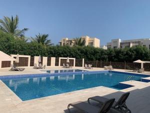 a large swimming pool with chairs and a building at Bait Al Marina in Salalah +2 photos