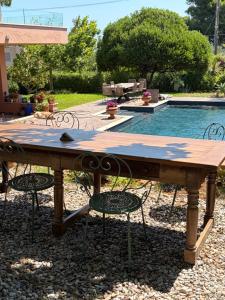 a wooden table with chairs and a swimming pool at Omma slow living villa in Rafina