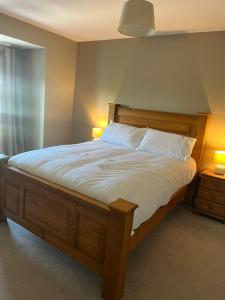 a bedroom with a wooden bed with two lamps and a bed sidx sidx at Sruthan na Teorainn in Carraroe