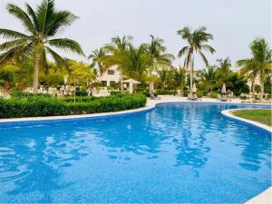 a large blue swimming pool with palm trees in the background at Bait Al Marina in Salalah