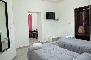 biały pokój z 2 łóżkami i telewizorem w obiekcie Bed & Breakfast Ellenica w mieście Rionero in Vulture