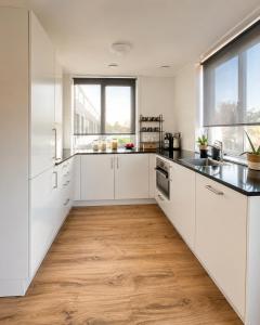 a kitchen with white cabinets and a wooden floor at Noordwijk BB228 in Noordwijk
