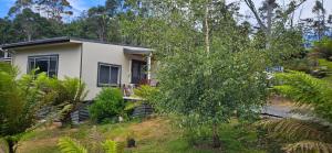 a small white house on a hill with trees at Cradle Alpine Retreat in Moina