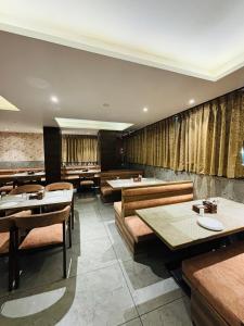 a dining room with tables and chairs and curtains at Pancharatna Regency in Chinchwad