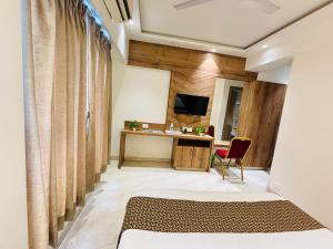 a bedroom with a bed and a desk with a television at Pancharatna Regency in Chinchwad