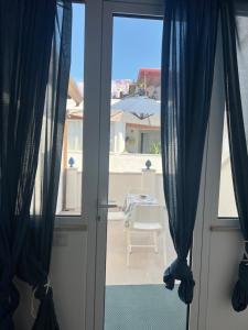 an open door to a patio with blue curtains at Camilla Lipari House - Canneto in Lipari +15 photos
