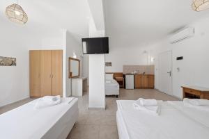 a white room with two beds and a kitchen at The Kavos Sandy Inn in Kavos