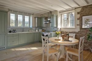 a kitchen with green cabinets and a table and chairs at North Lodge at Pudleston Court in Hatfield