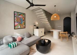 a living room with a couch and a staircase at The Arc House Canggu in Canggu