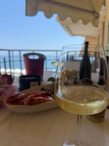 a glass of wine on a table with a plate of food at Victoria Beach Front de Mer Luxury Apartment in Menton