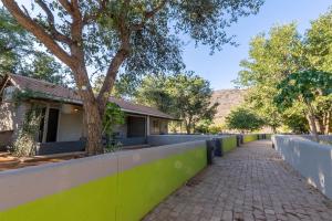 a retaining wall next to a house with a tree at Gondwana Damara Mopane Lodge in Mopane Pos