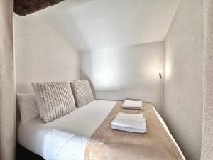 a small white bed with two towels on it at L'étincelle de Camargue, Plage et centre à pied in Saintes-Maries-de-la-Mer