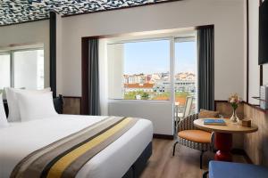 a hotel room with a bed and a table and a window at Avani Avenida Liberdade Lisbon Hotel in Lisbon