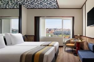 a hotel room with two beds and a window at Avani Avenida Liberdade Lisbon Hotel in Lisbon