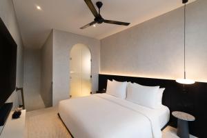 a bedroom with a white bed and a ceiling fan at The Arc House Canggu in Canggu