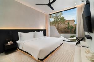 a bedroom with a white bed and a large window at The Arc House Canggu in Canggu