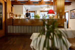 a man standing behind a bar in a restaurant at Royal Olympic Hotel in Pinzolo +151 photos