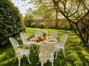 a white table and chairs in a yard at La spacieuse maison des miots in Saint-Simeux